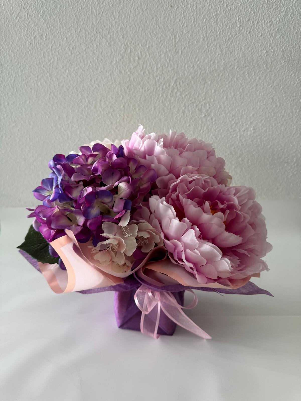 Artificial floral arrangement featuring purple, pink, and white flowers