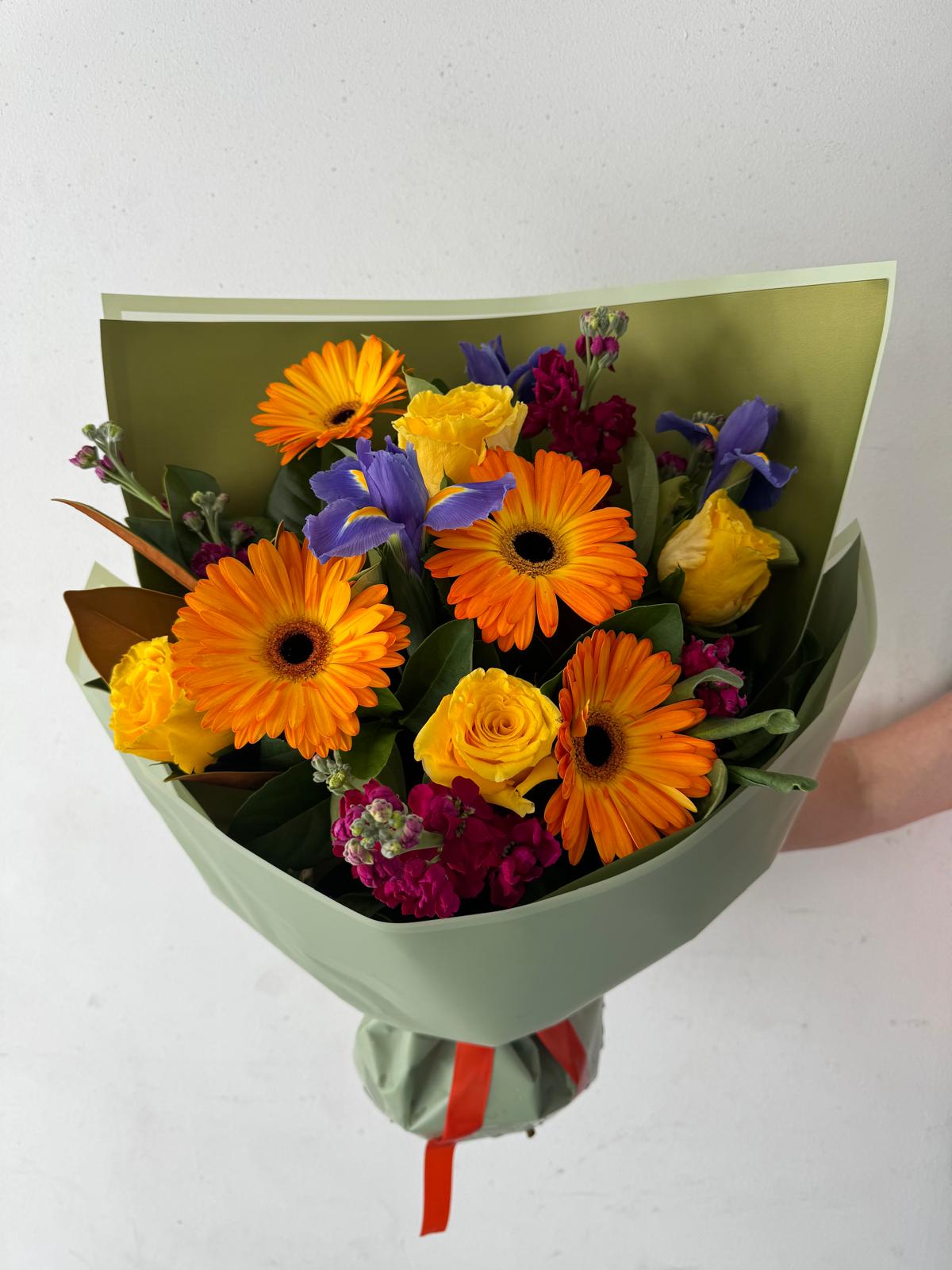 A bouquet of flowers with bright seasonal colors, including orange, yellow, and purple flowers