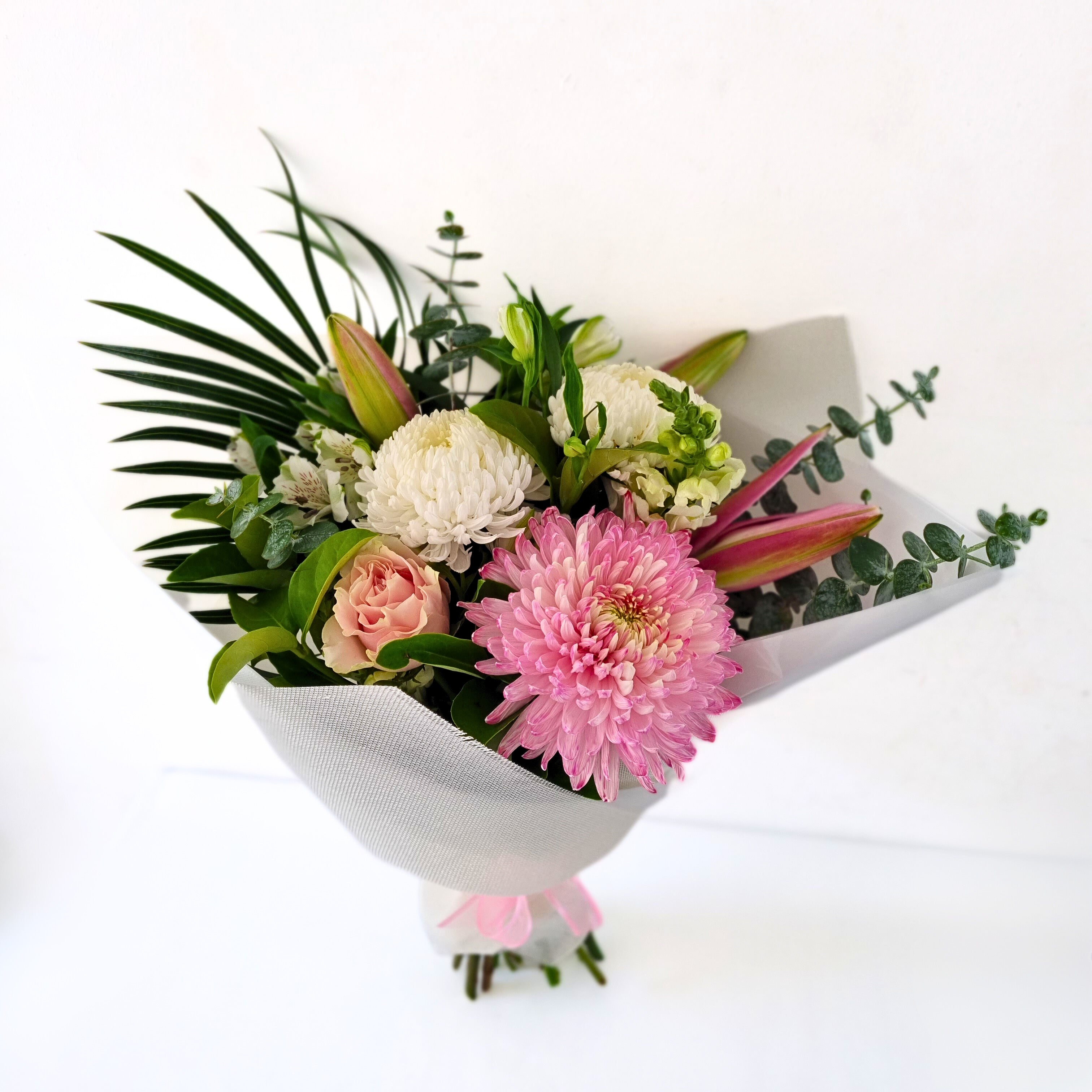 A bouquet featuring with soft pastel mixed seasonal blooms, with a variety of flowers